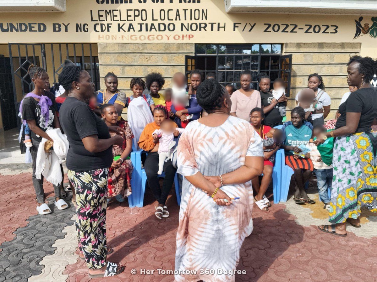 Mothers seated and standing in a circle, listening during the workshop